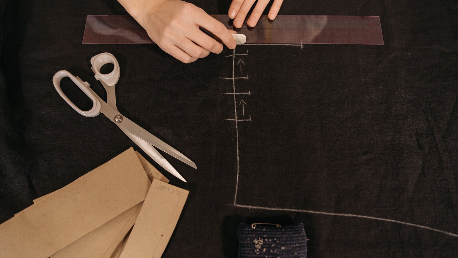 Tailor shears and chalk resting on folded grey wool cloth