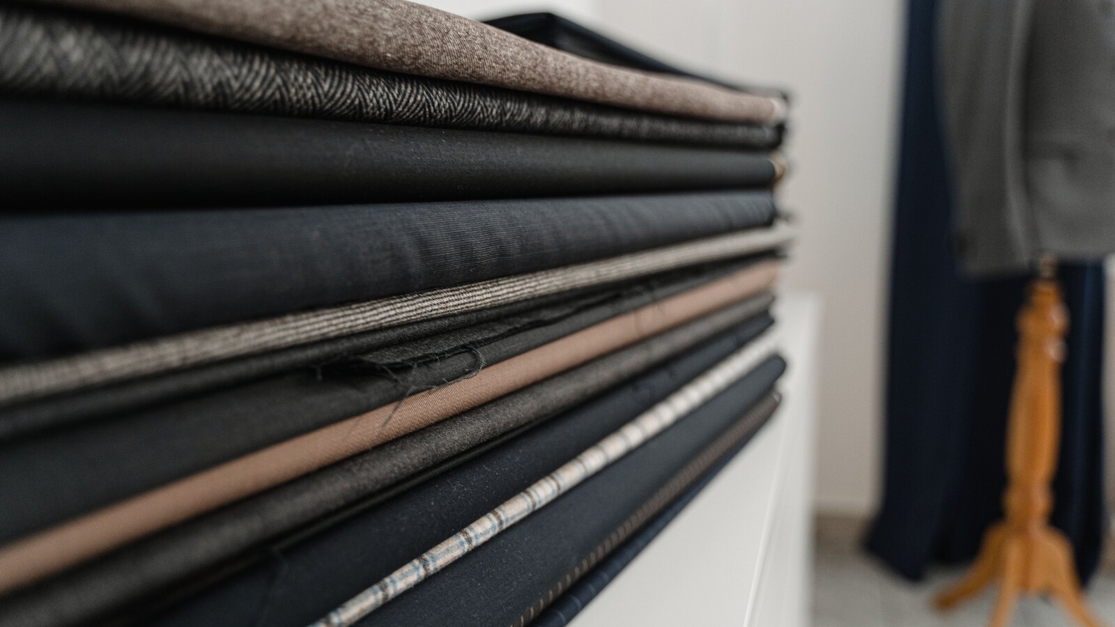 Rolls of wool suiting cloth stacked on a shelf